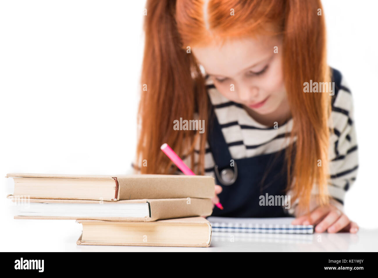 close-up view of books on desk and schoolgirl drawing with felt tip pen ...