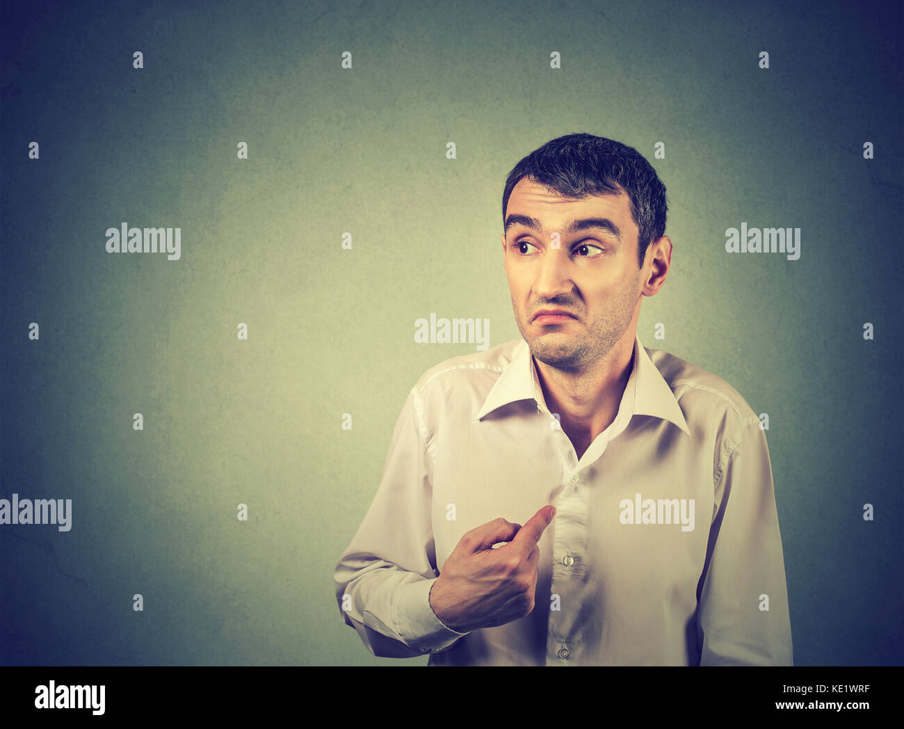 young guy pointing at himself you mean me isolated on gray background. Human emotion facial expression feeling Stock Photo