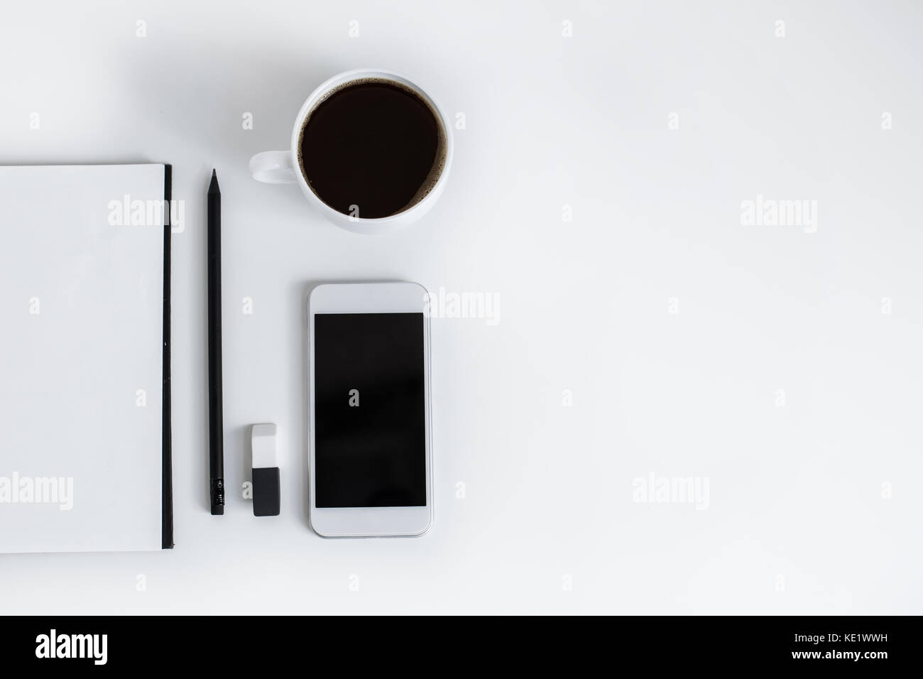 top view of notepad, smartphone with blank screen and cup of coffee ...