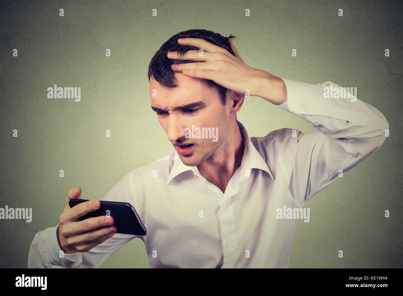 Closeup portrait, shocked man feeling head, surprised he is losing hair, receding hairline, bad news isolated on gray wall background. Negative facial Stock Photo