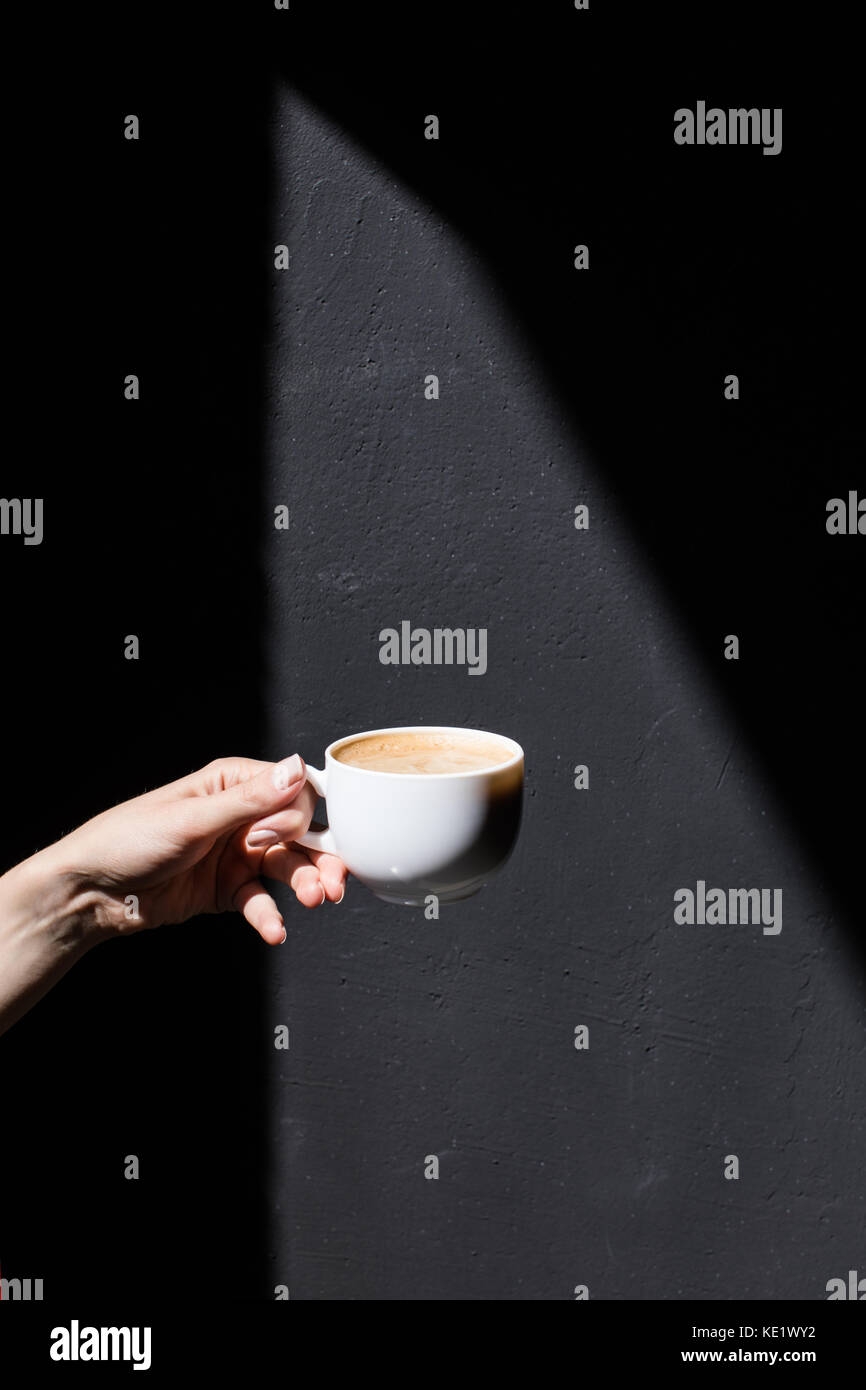 cropped view of person holding cup of coffee on black Stock Photo