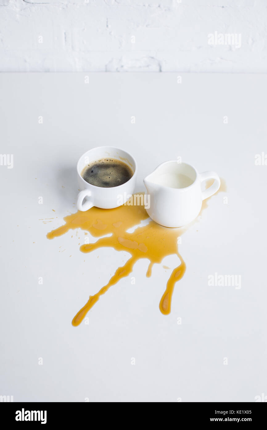 cup of coffee and milk jar with coffee stain on white tabletop Stock Photo
