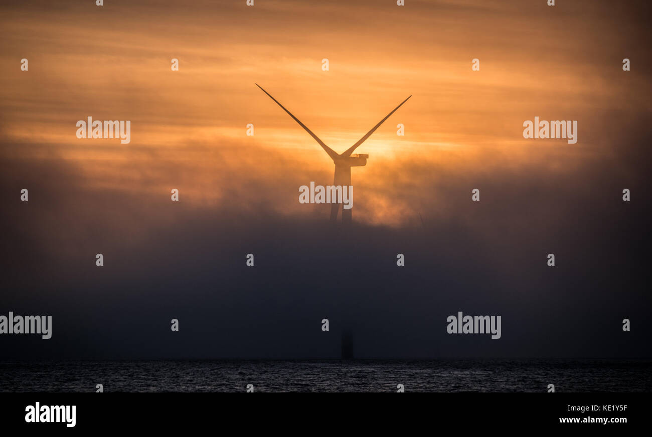 A wind turbine on Walney Extension Offshore Wind Farm shrouded in fog during sunset Stock Photo