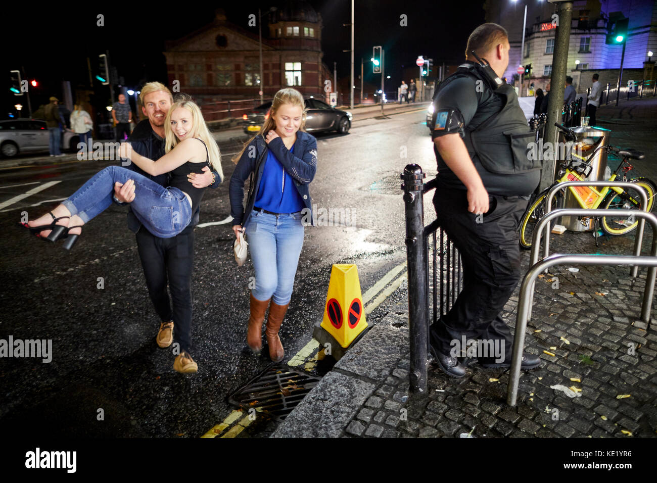 Late night a man carrying a young lady across Anchor Road in Bristol Stock Photo