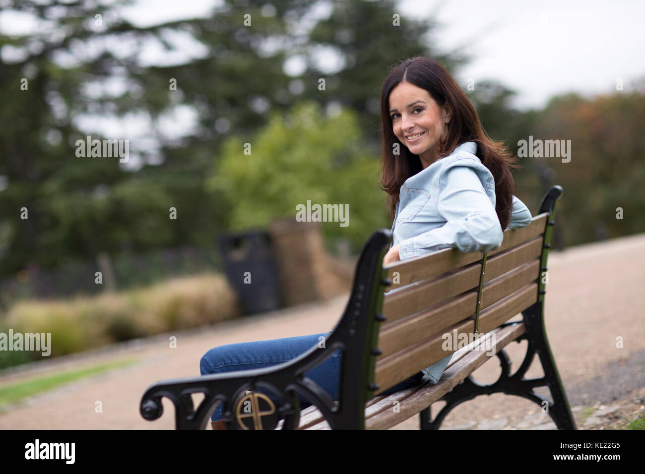 young woman sitting on a bench in the park Stock Photo - Alamy