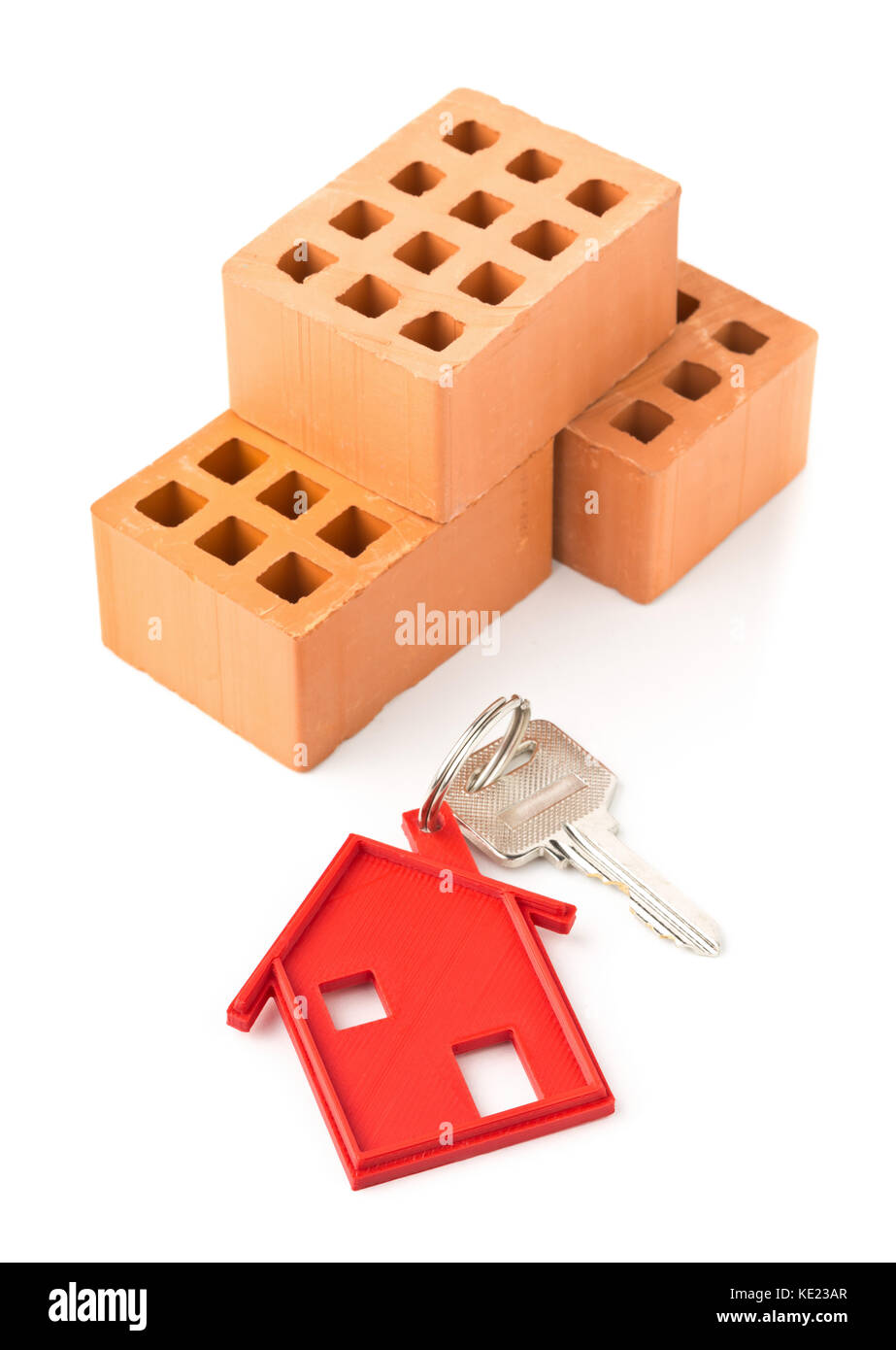 House door key with red house key chain pendant and bricks over white background Stock Photo