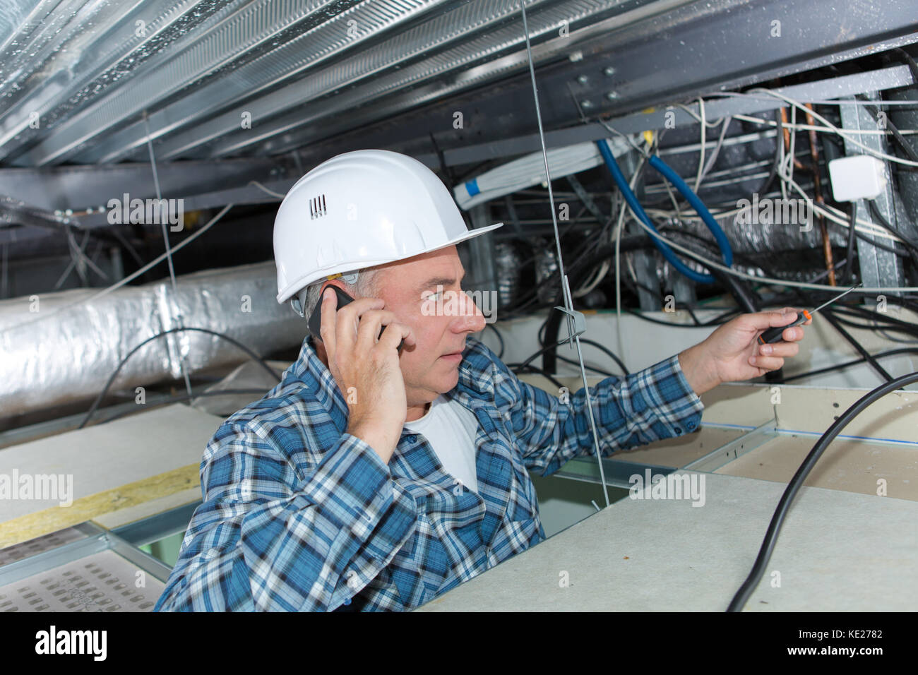 builder checkking ceilings cables while using the phone Stock Photo - Alamy