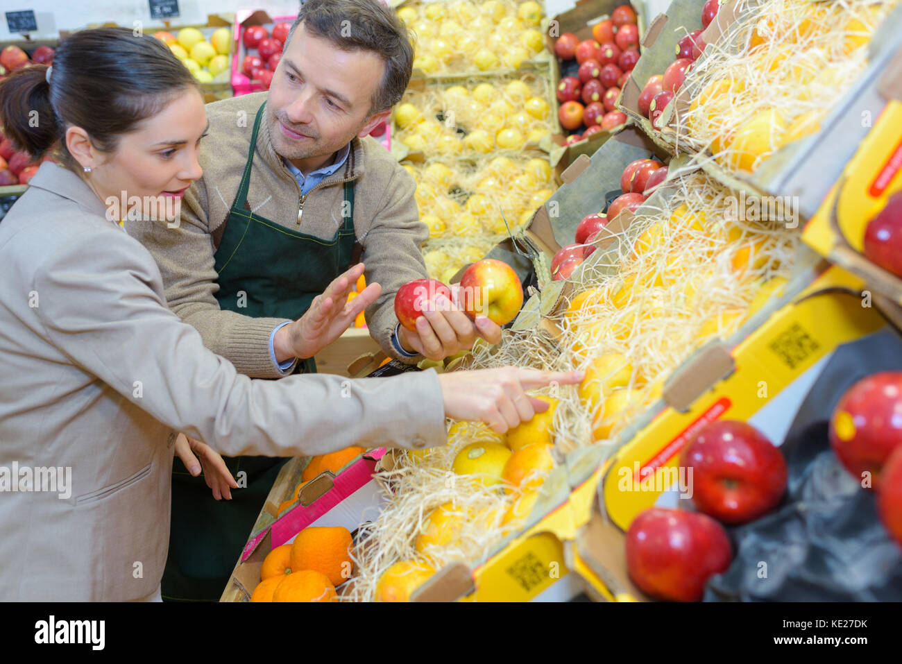 smiling woman choosing different fruits at farm food store display ...