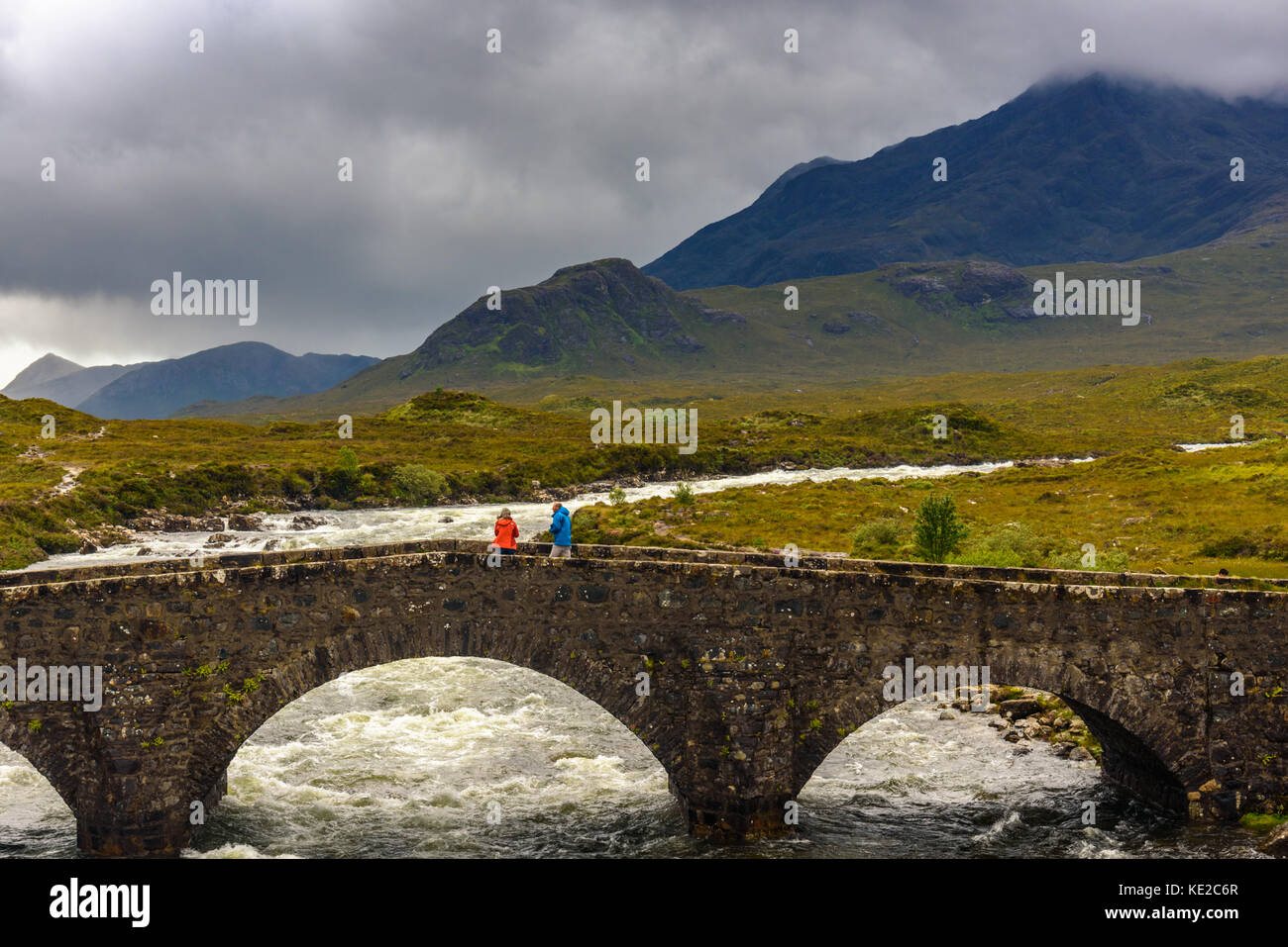 ISLE OF SKYE, SCOTLAND - AUGUST 11, 2017 - View of Sligachan bridge with Cuillins Hills on Isle of Skye with two tourists who look the panorama. Stock Photo