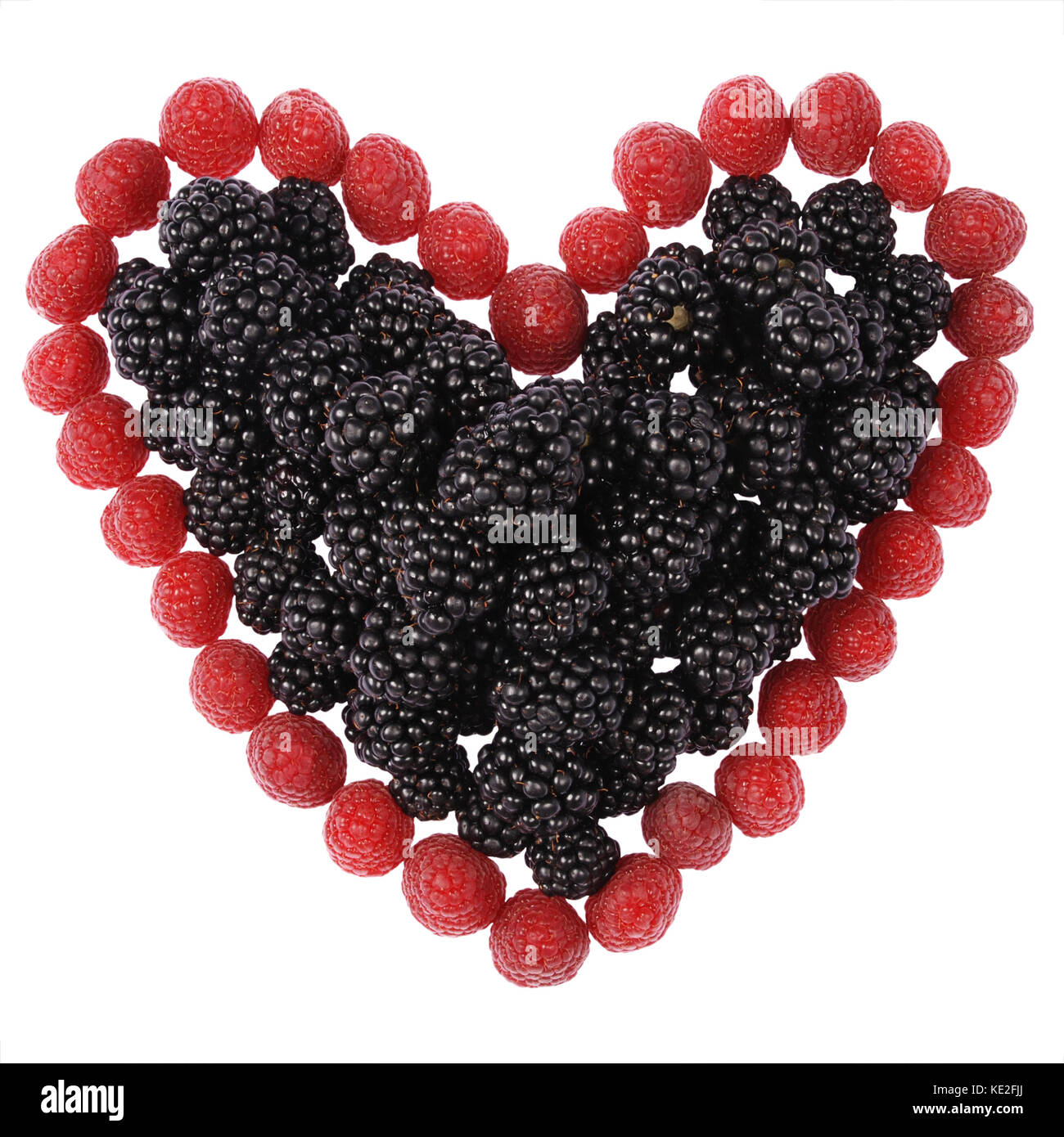 Heart made out of raspberries and blackberries on white background