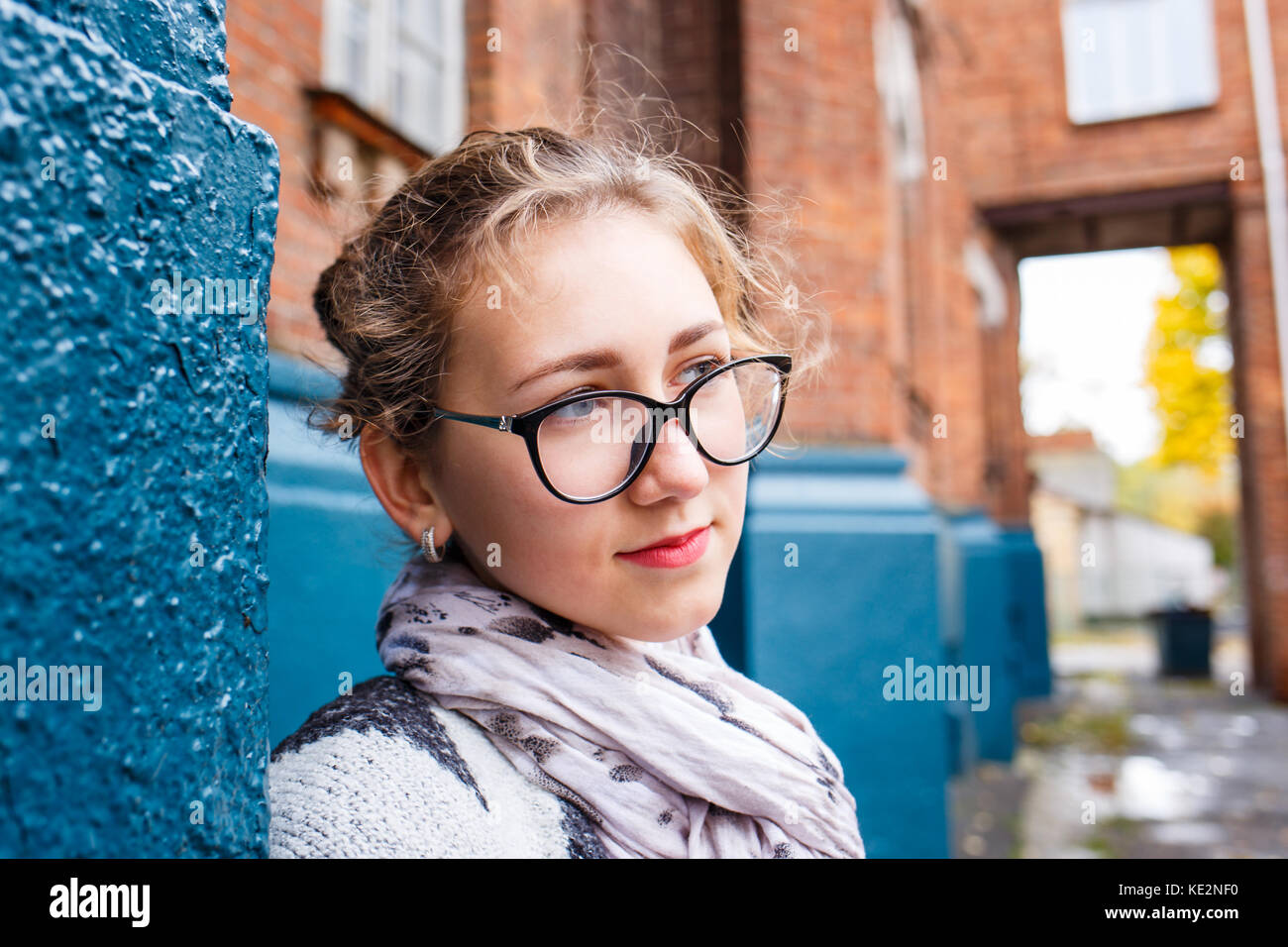 Young female student standing near college building in autumn. Education background with student girl and copy space Stock Photo