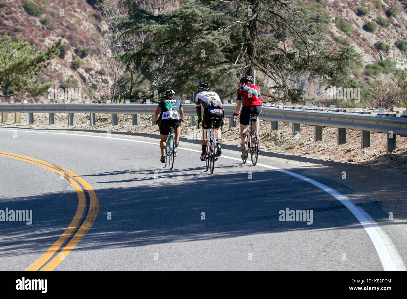 Bike riders on mountain highway in dangerous formation with fast treffic Stock Photo