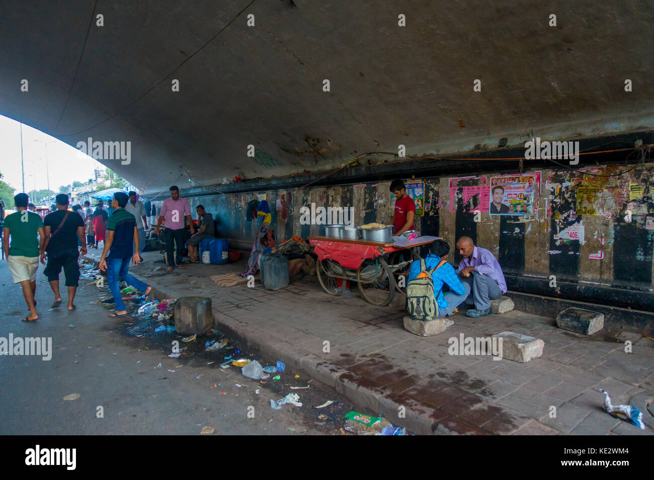 DELHI, INDIA - SEPTEMBER 25, 2017: Unidentified people living in the streets of the city under a bridge juveniles catching sleep on footpath, delhi, india Stock Photo