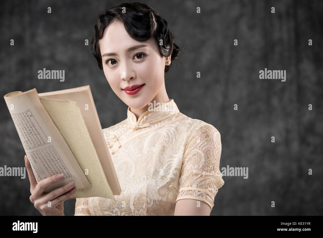 Portrait of young smiling woman in retro-style oriental clothes posing with book Stock Photo