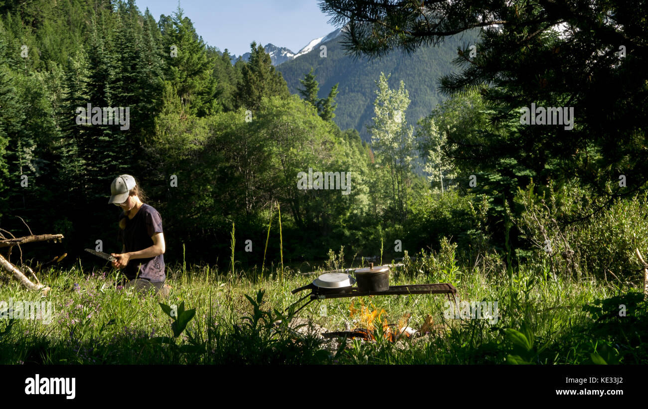 A girl preparing firewood with a handsaw for the camp fire - the South Chilcotin Mountain Park, BC, Canada Stock Photo