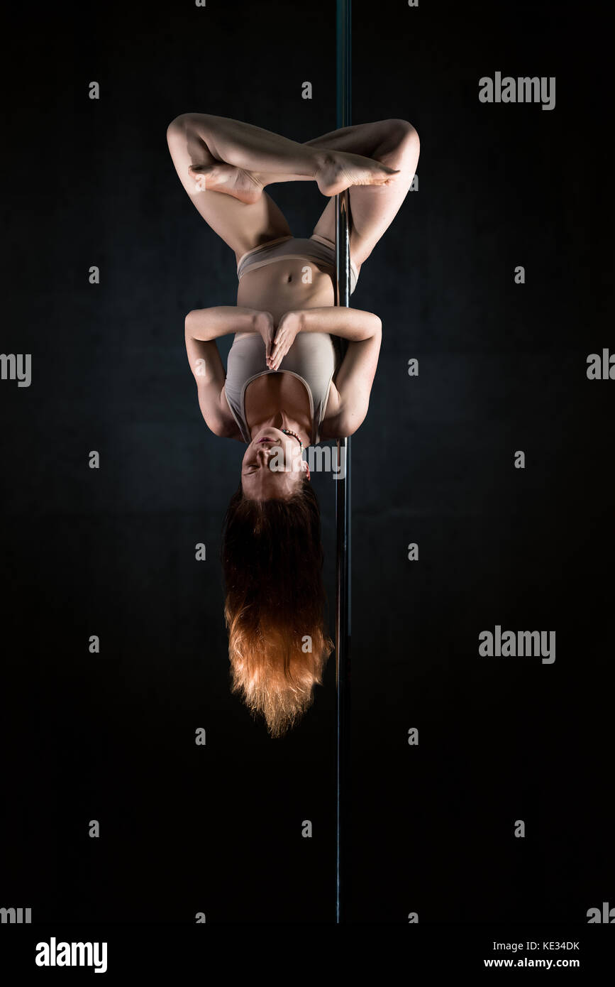 Young woman in meditation Lotus position upside down on pole Stock Photo