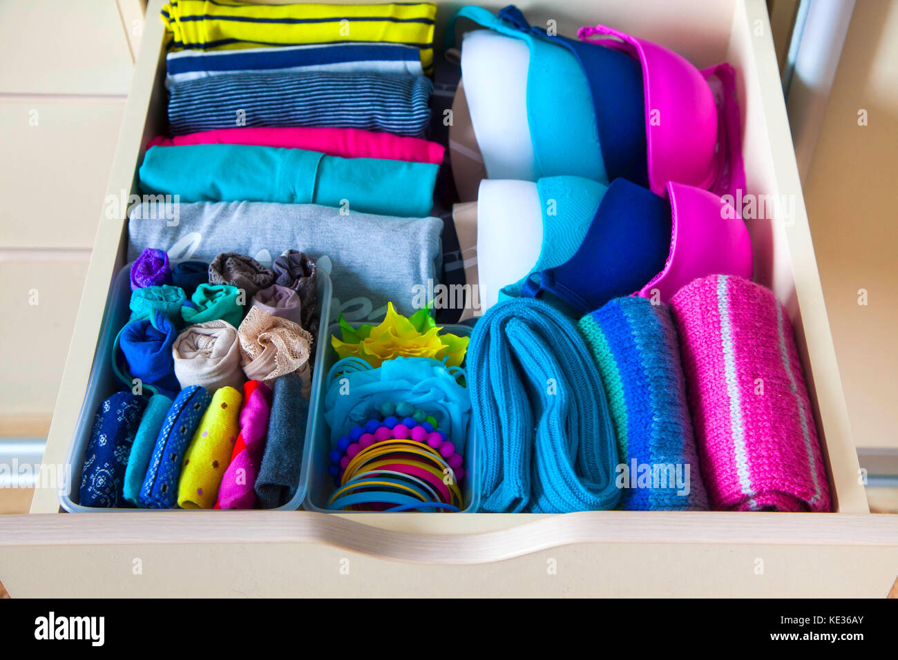 Neatly folded clothes with accessories in chest of drawers Stock Photo
