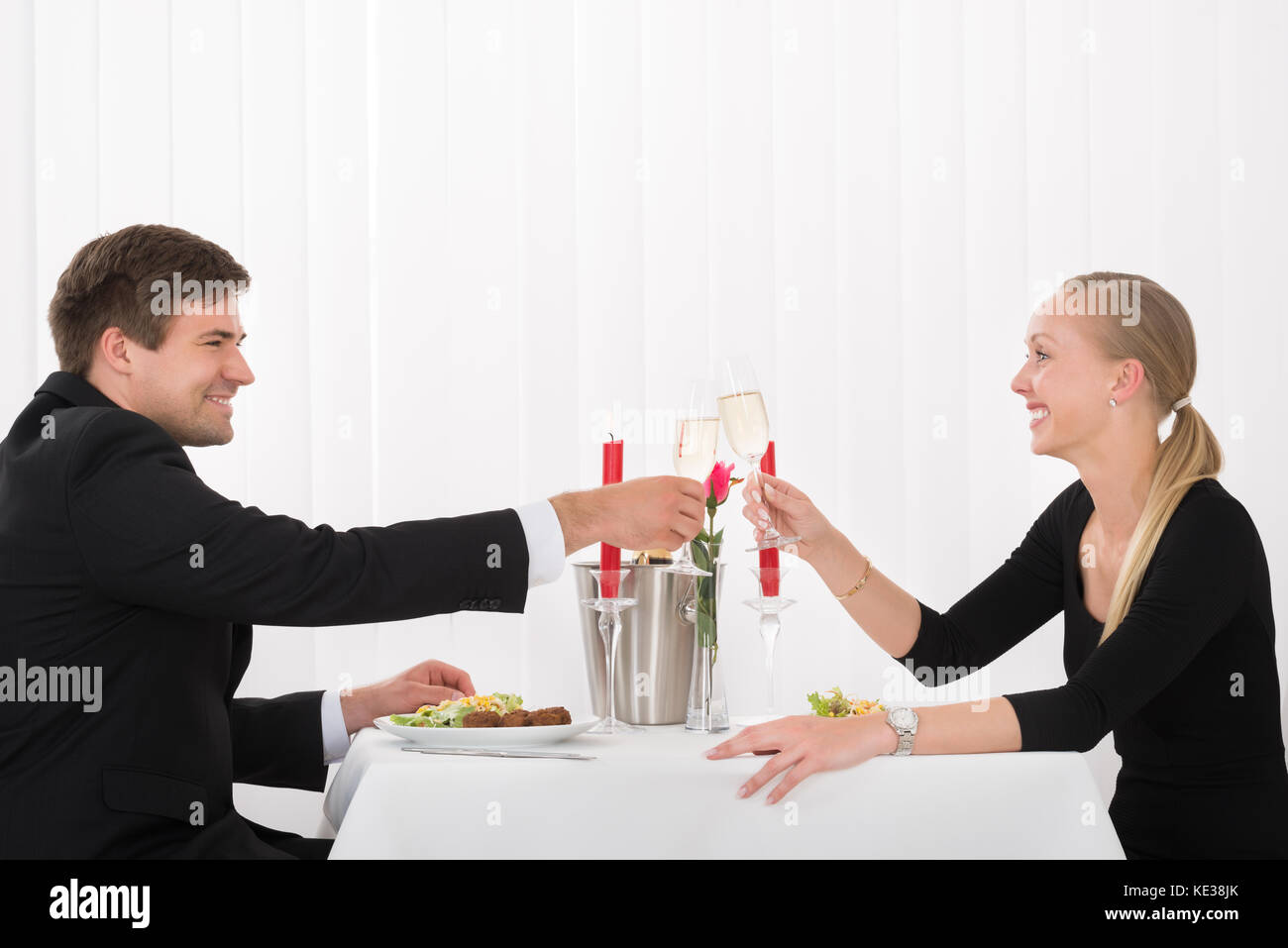 Young Happy Couple Toasting Glass Of Champagne In Restaurant Stock Photo
