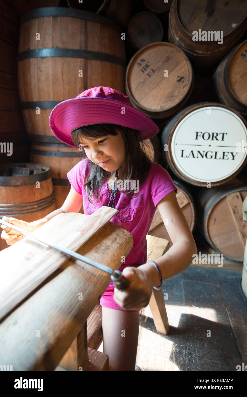 Girl shaping a barrel stave in the cooperage at Fort Langley National Historic Site. Fort Langley, BC, Canada. Stock Photo