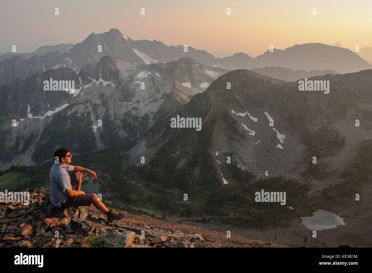 Hiker watching the sunset over the Cascade Mountains at the summit of Frosty Mountain in Manning provincial park, British Columbia, Canada Stock Photo