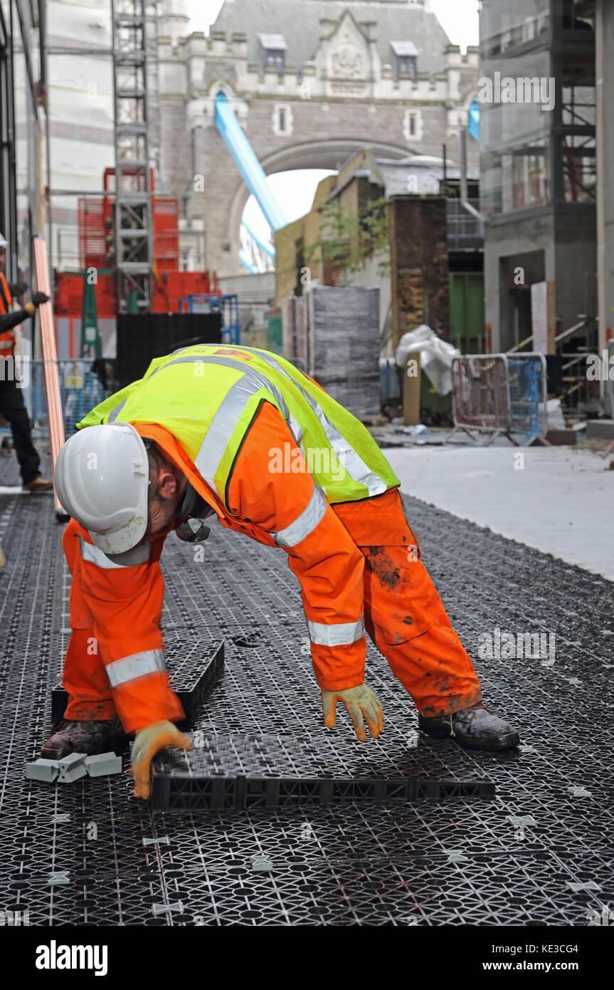 Workman installing cellular drainage blocks on a central London residential development to create instant drainage of a large paved area above. Stock Photo
