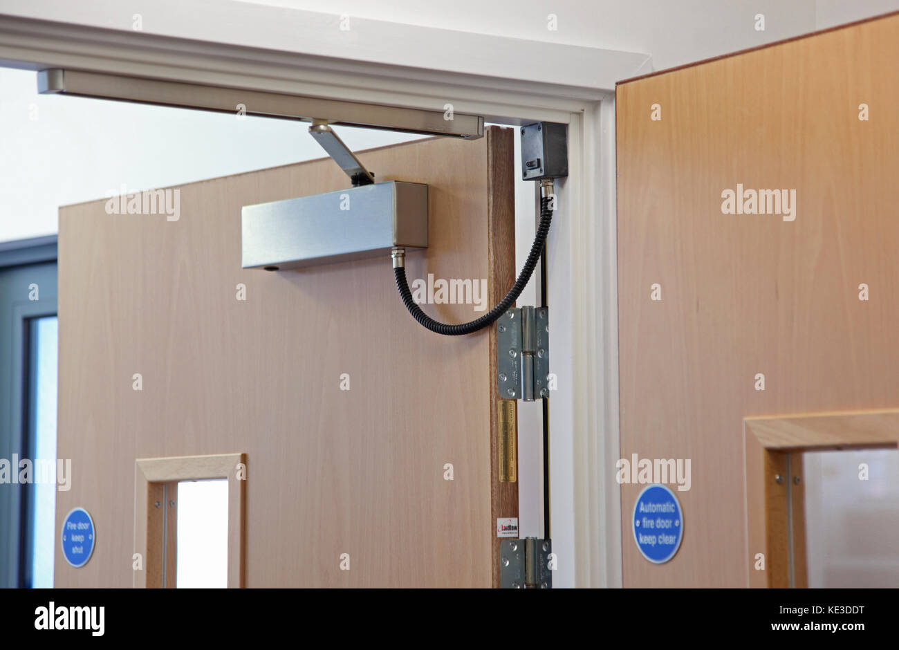 Close-up of an electronically operated, magnetic fire door closer on interior doors in a UK college building. Stock Photo