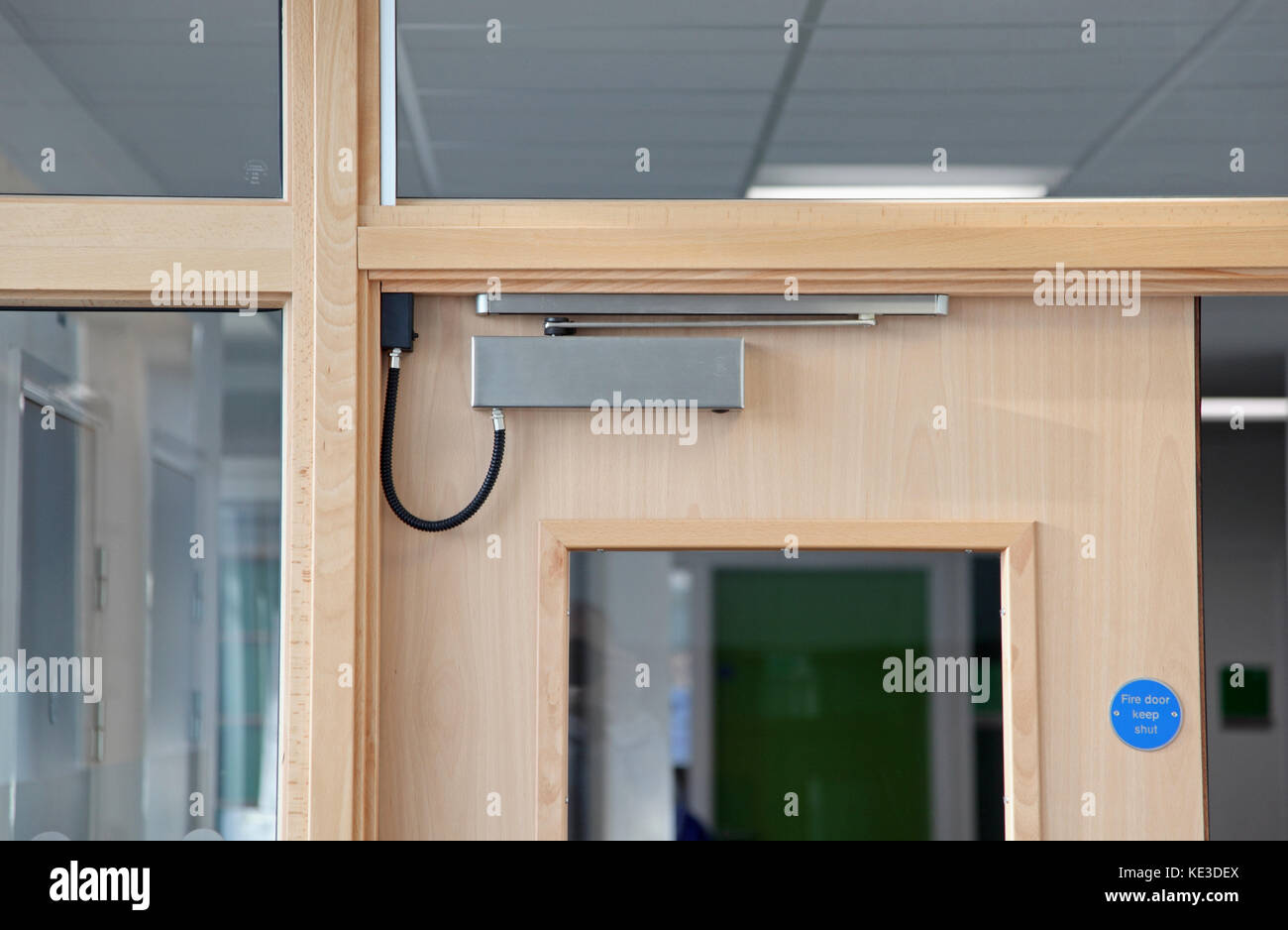 Close-up of an electronically operated, magnetic fire door closer on interior doors in a UK college building. Stock Photo