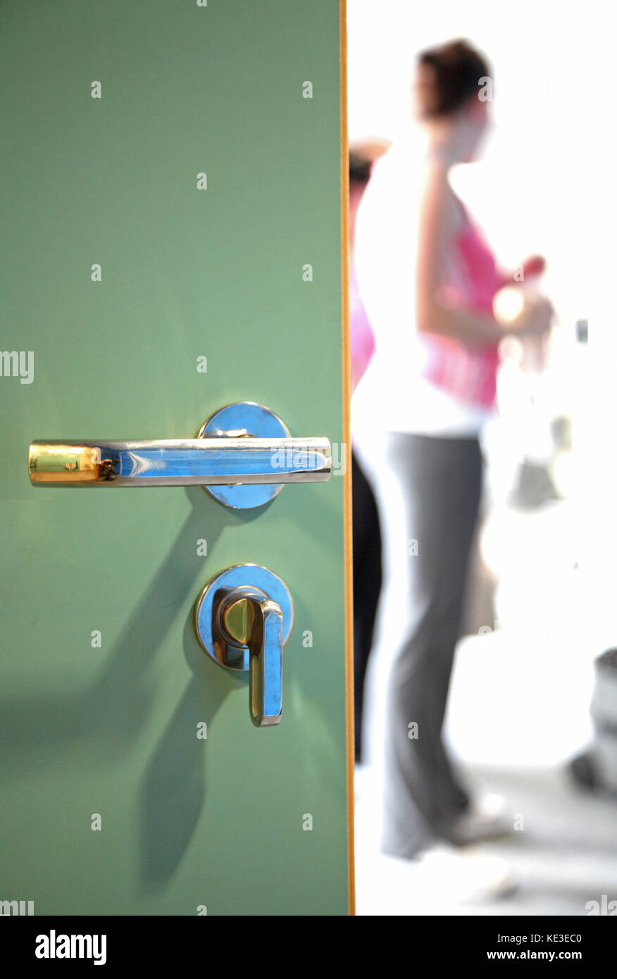 Close-up of changing room door in a UK sports centre. Shows handle and hand-operated lock, customers beyond (shown out of focus) Stock Photo