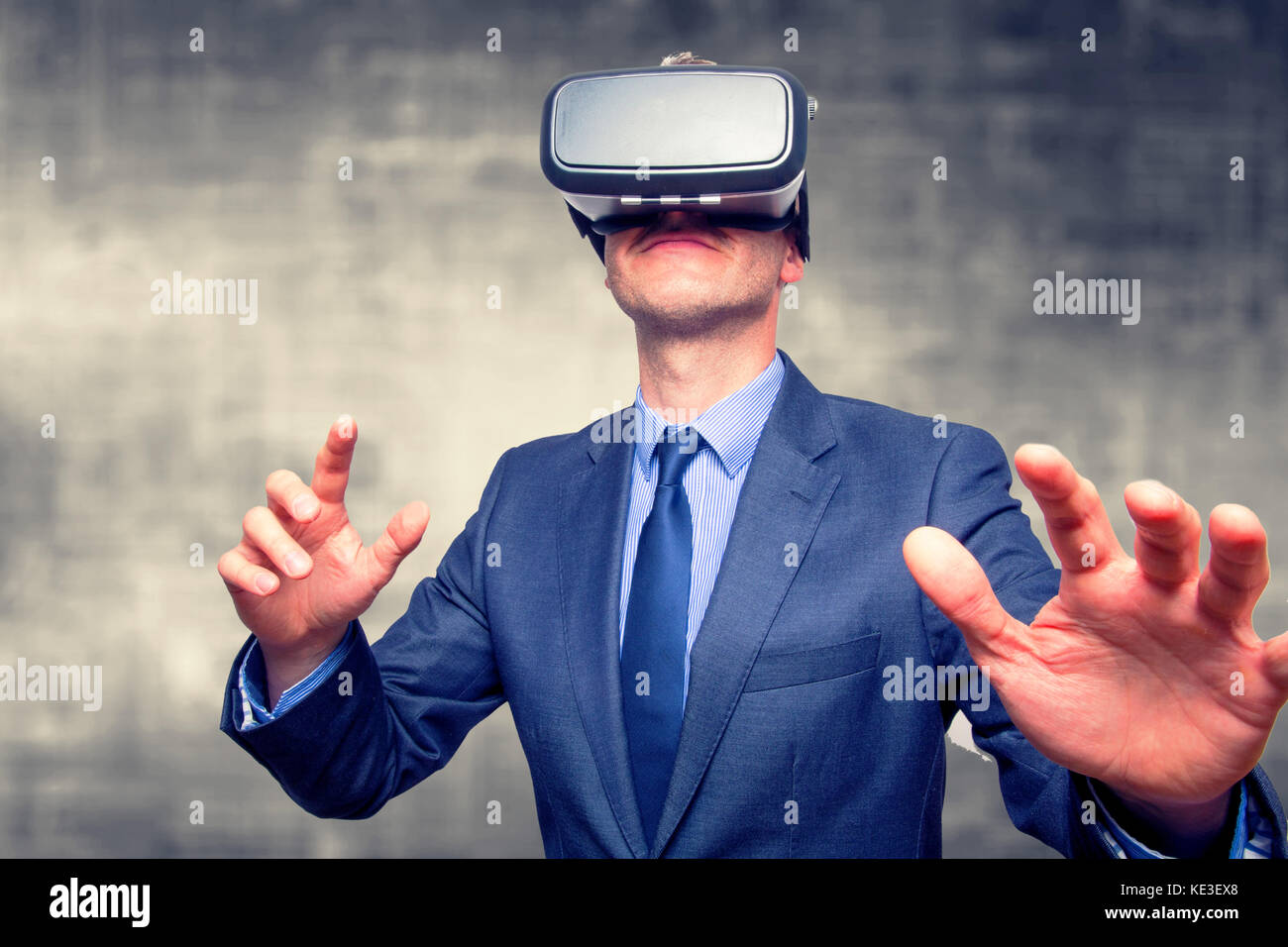Businessman in a suit wearing Virtual Reality Goggles isolated on grey ...