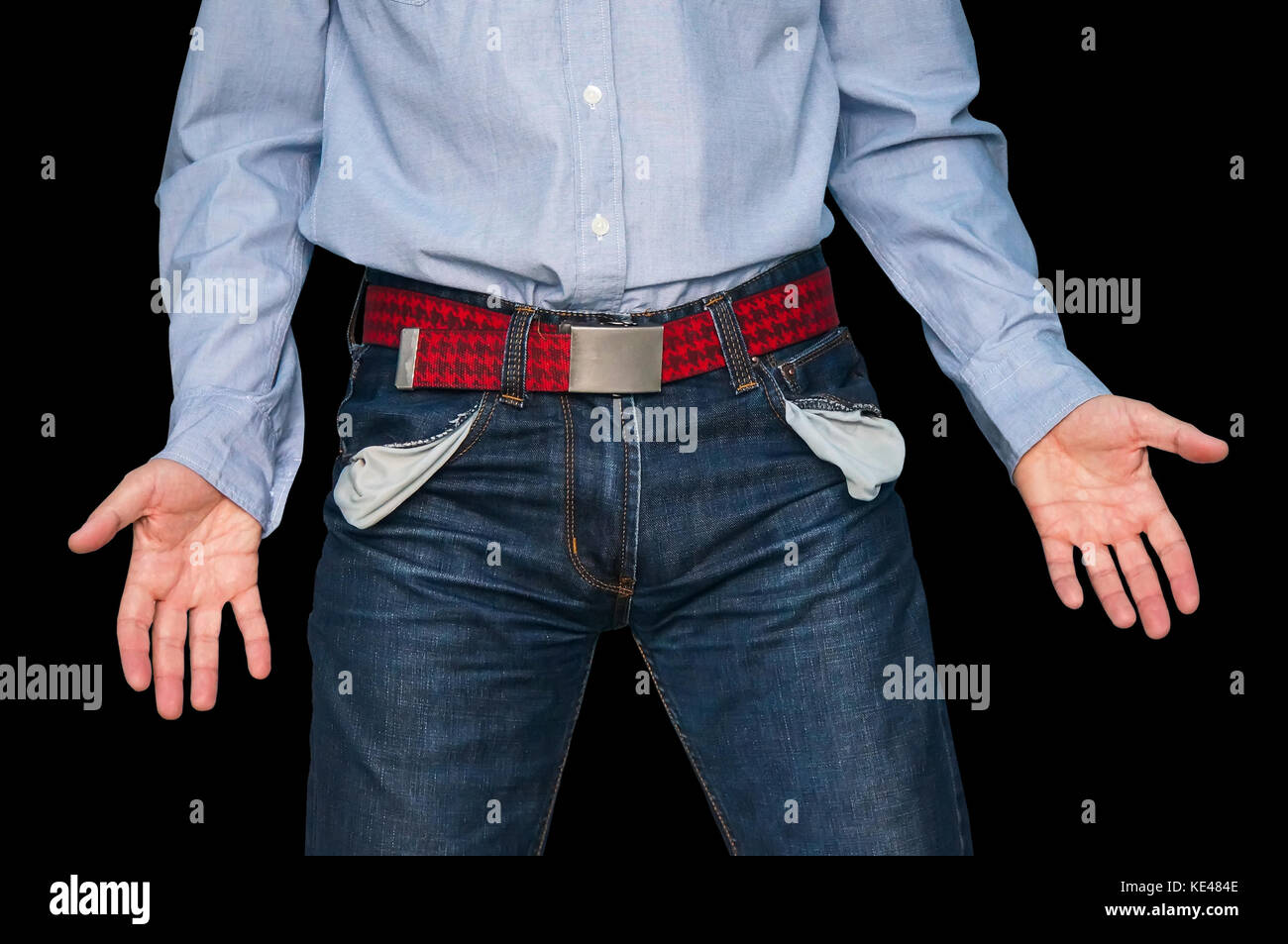 man showing his empty pockets demonstrating he has no money on black isolated background. The guy throws his hands to the sides show the inconsistency Stock Photo
