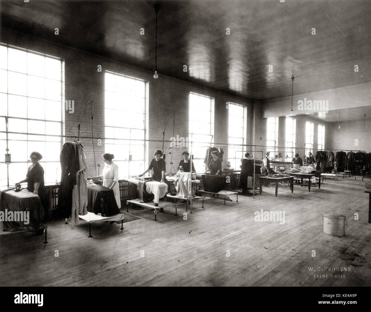 This photograph depicts women working in the pressing department of Lungstras Dyeing and Cleaning Company, reflecting early 20th-century labor conditions and the role of women in industrial work environments. Stock Photo