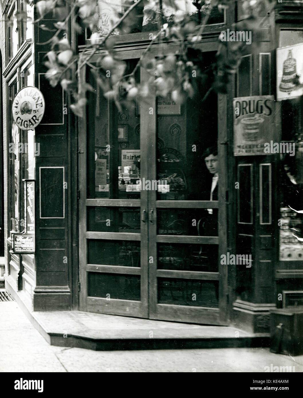 Young man looks out through the screen doors of W. C. Kalis Drugstore