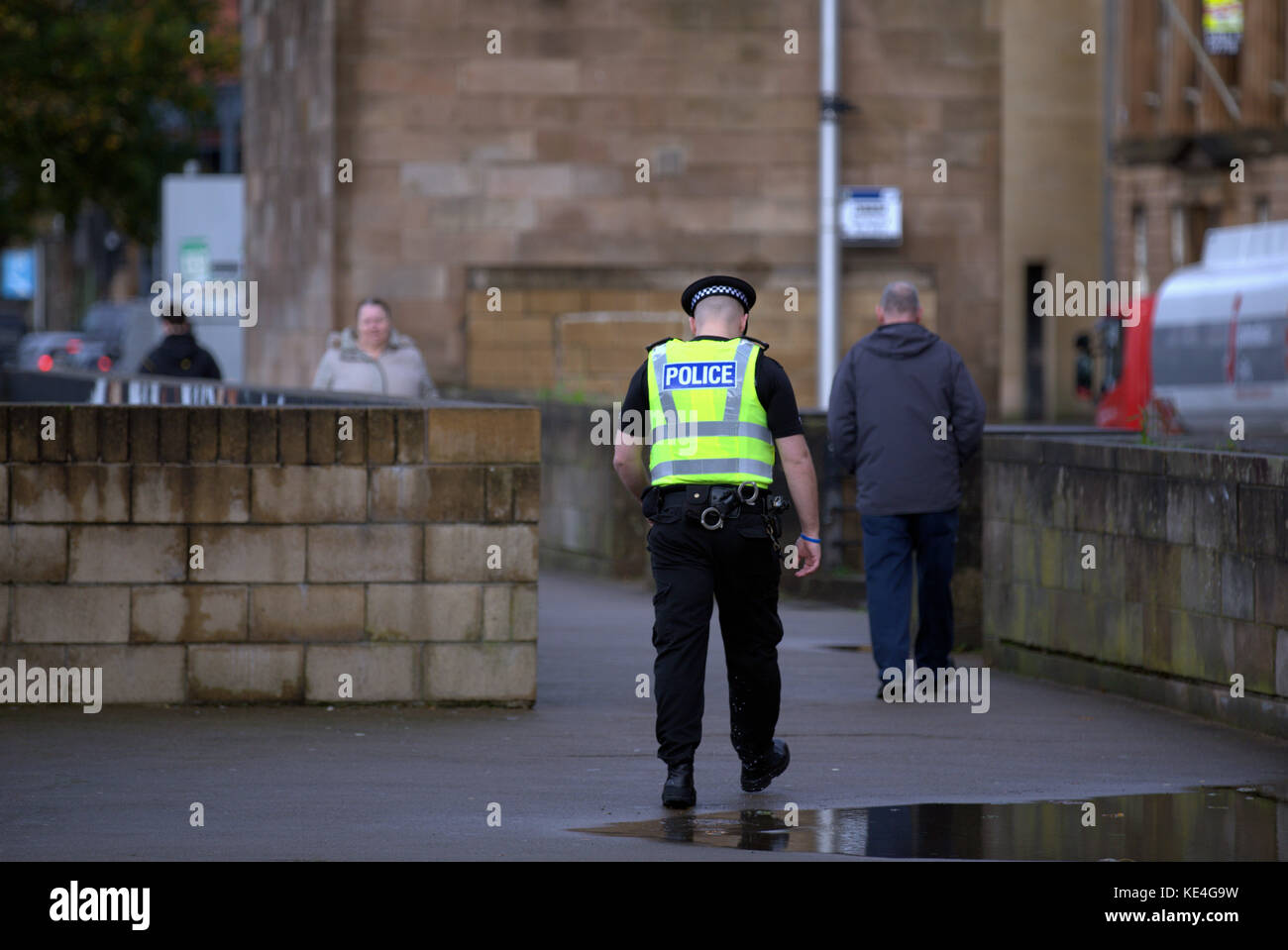 policeman police scotland walking beat  on clyde walkway viewed from behind on tradeston bridge Stock Photo