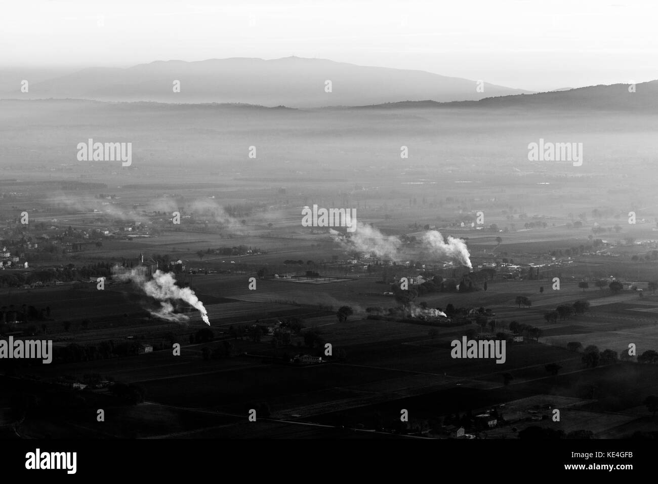 A valley in Umbria at sunset, with some smoke and mist, distant hills and soft tones Stock Photo
