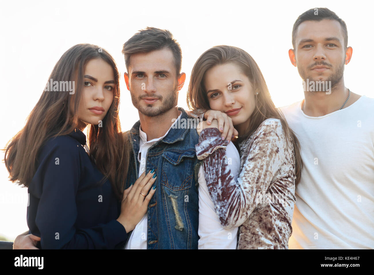 Two women and men outdoors on sunny day. Happy people standing close to ...
