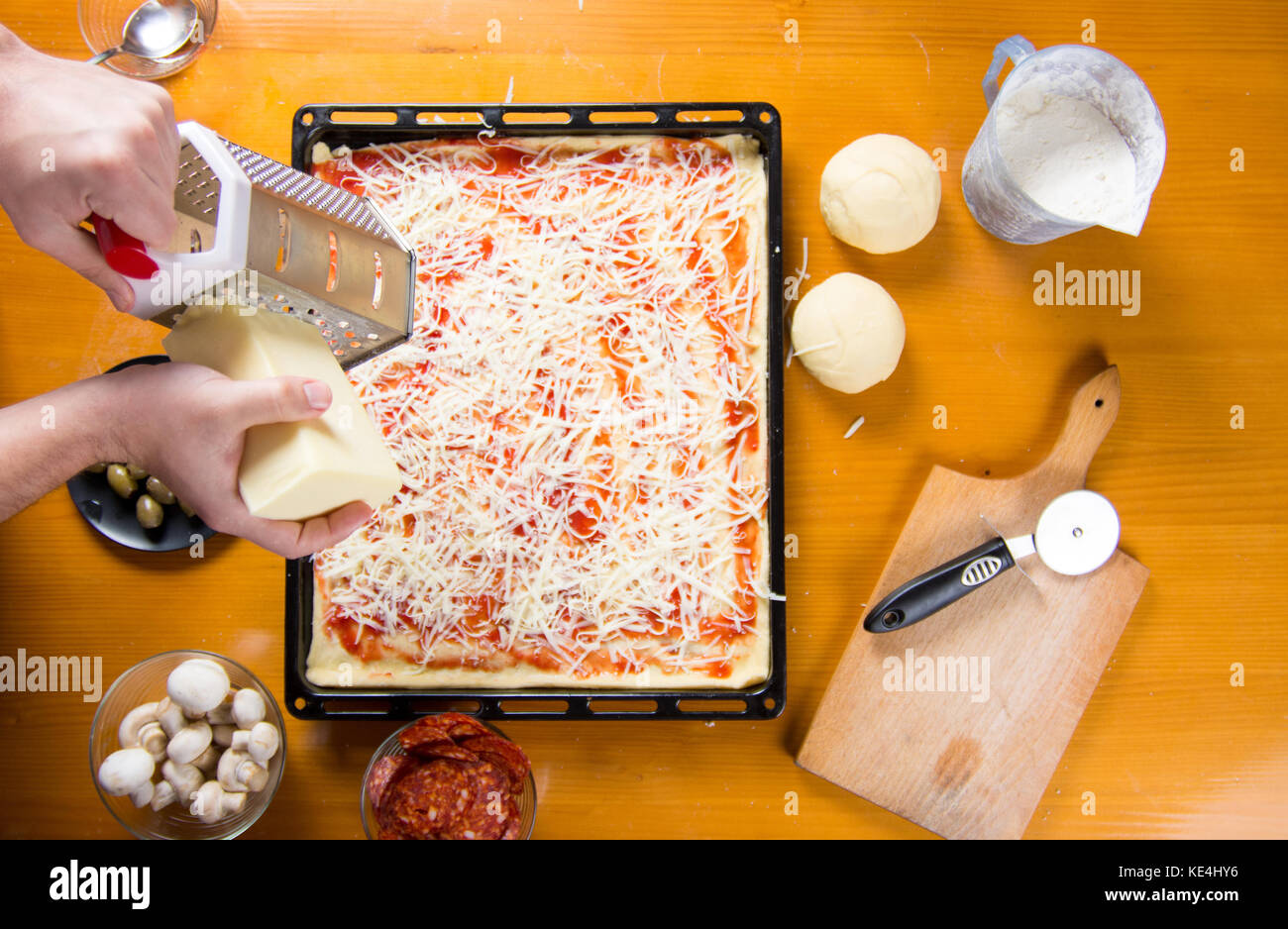Man grating cheese on a pizza base. Making pizza Stock Photo