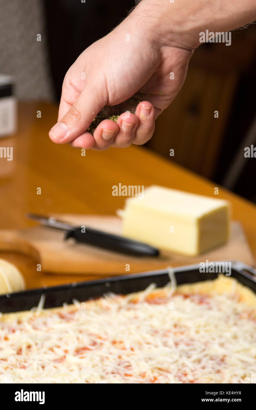 Man putting oregano on to pizza Stock Photo