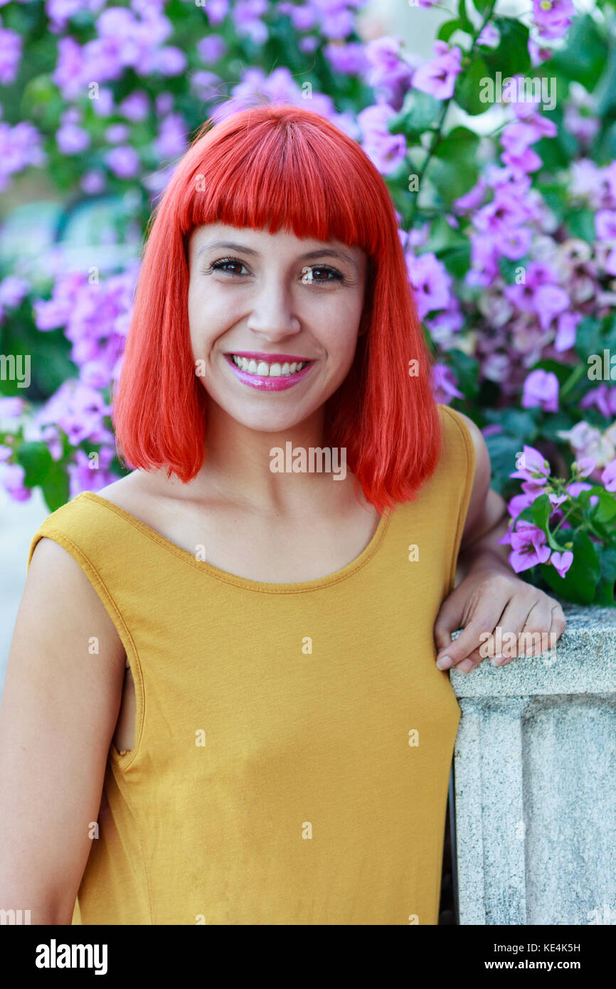 Happy woman with red hair and yellow dress near to a plant with ...