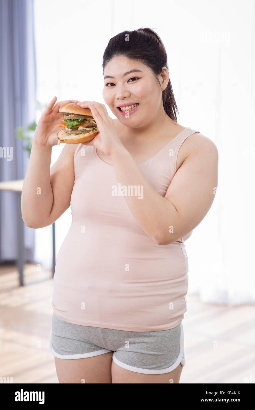 Young smiling fat woman with a hamburger posing Stock Photo