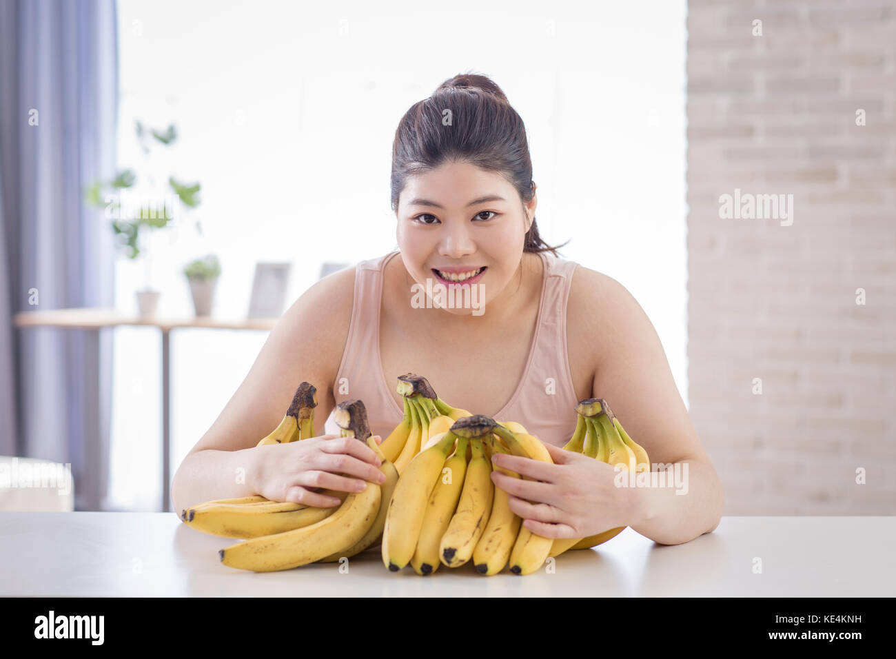 Portrait of young smiling fat woman with bananas Stock Photo