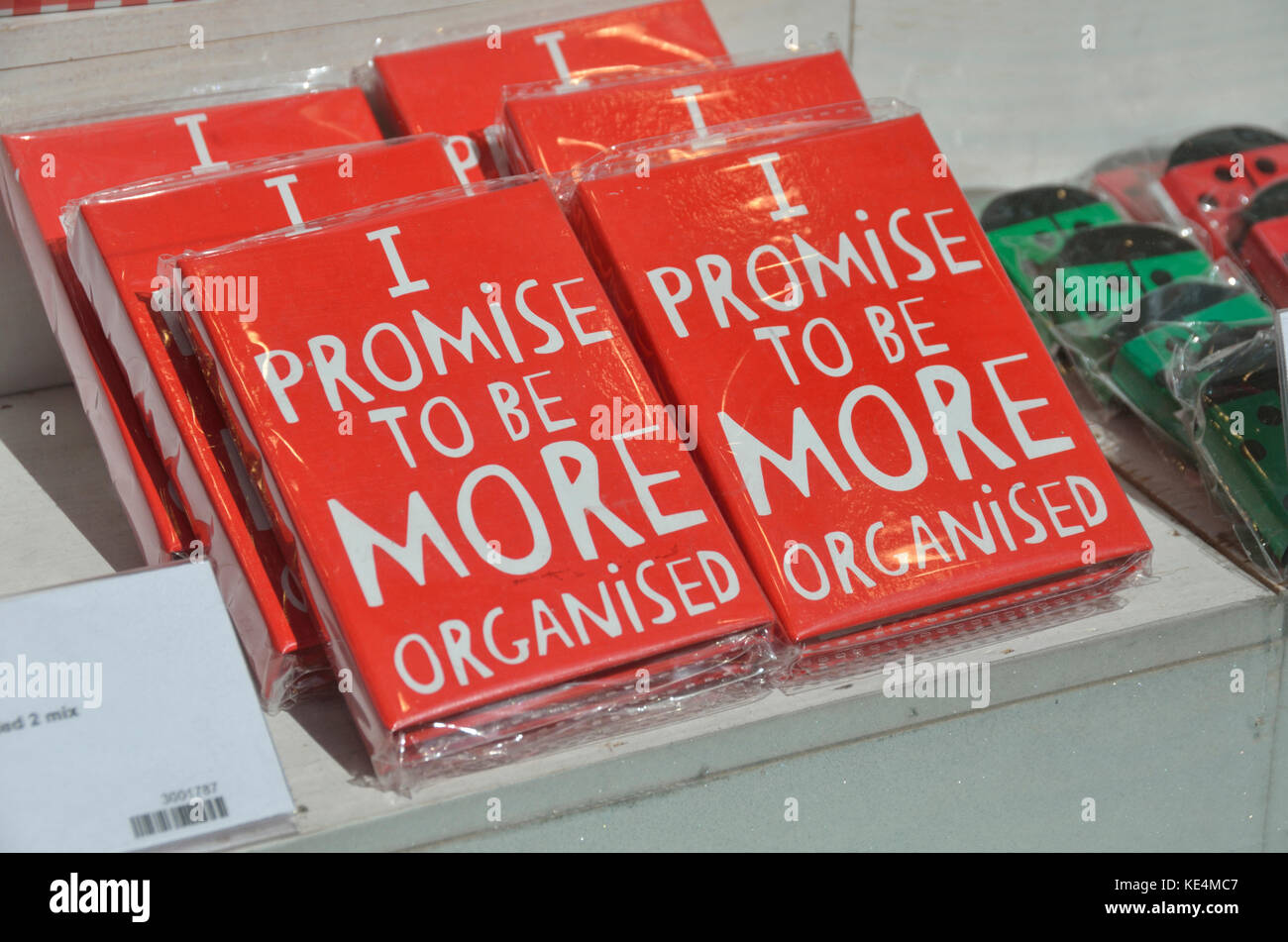 Red notebooks displaying the slogan ’I promise to be more organised’. Stock Photo