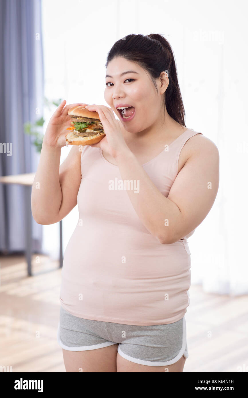 Young smiling fat woman eating fast-food Stock Photo