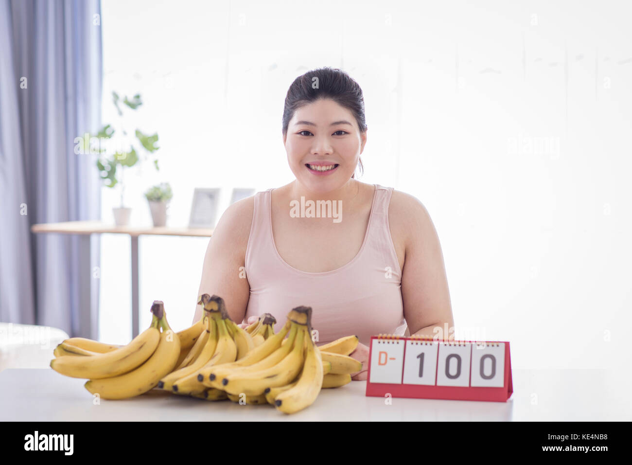 Portrait of young smiling fat woman making diet plan with bananas Stock Photo
