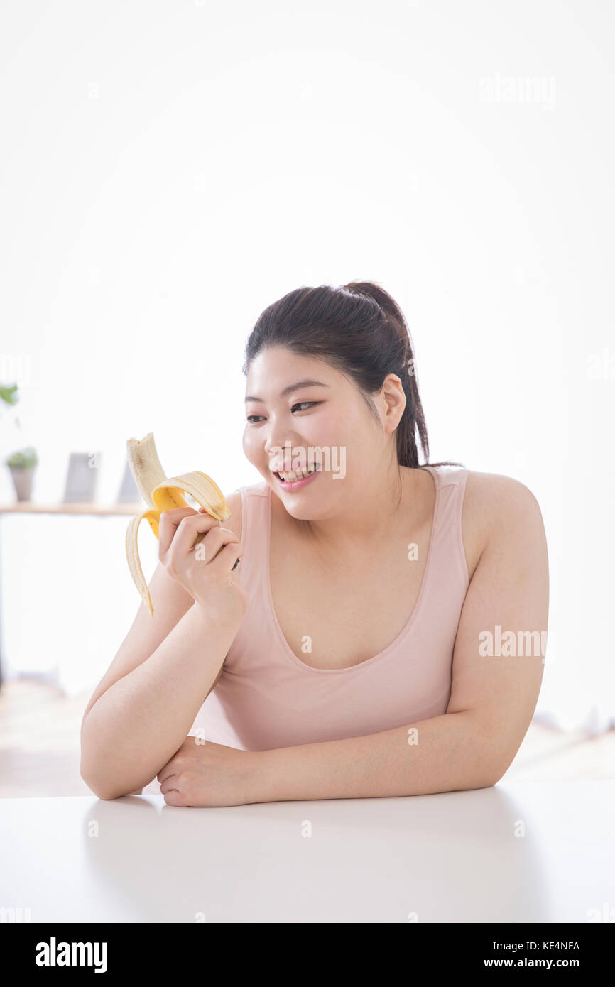 Portrait of young smiling fat woman eati banana Stock Photo