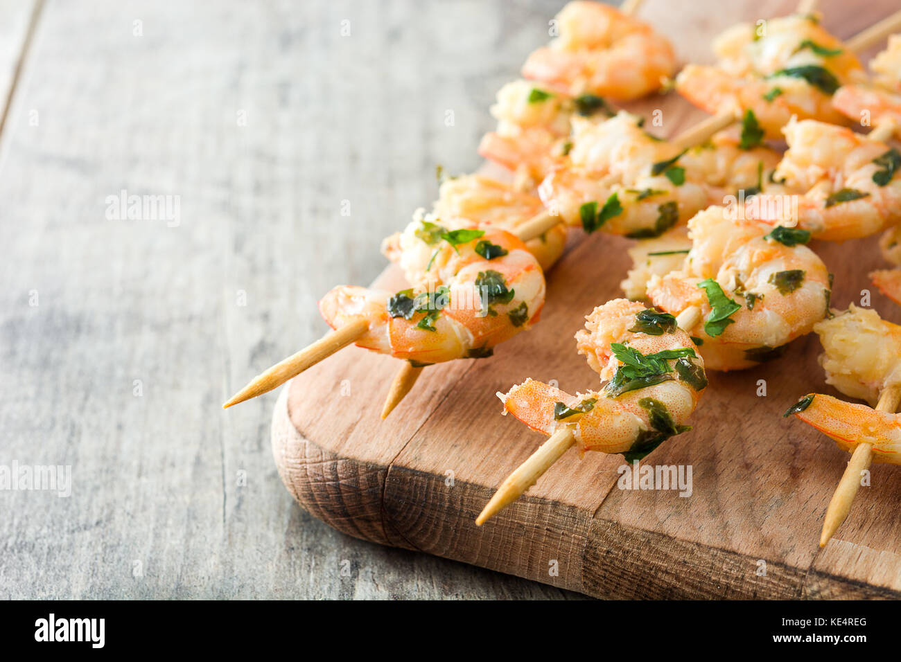 Shrimp skewers on wooden table Stock Photo