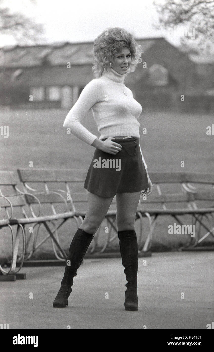 1960s, historical, shapely blonde woman with big wavy hair posing outside in a black mini skirt and knee length boots. Stock Photo