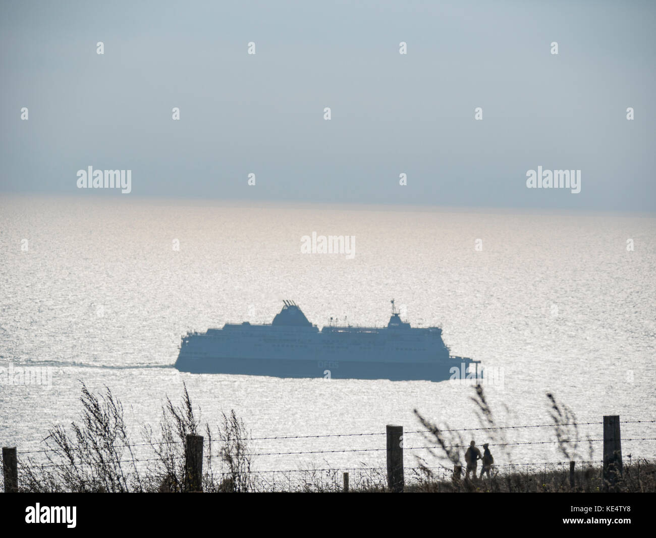 Ferry at Dover Port taken from the cliffs with silhouette of walkers Stock Photo