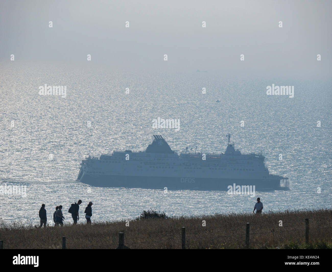 Ferry at Dover Port taken from the cliffs with silhouette of walkers Stock Photo