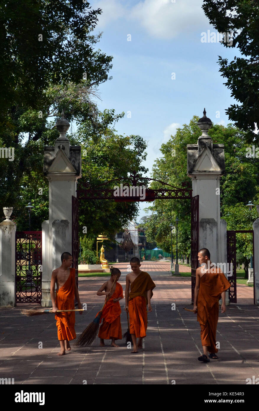 Young monks are interacting with each other in Bang Pa-In, Thailand. They're even bringing some brooms! Pic was taken in August 2015. Stock Photo