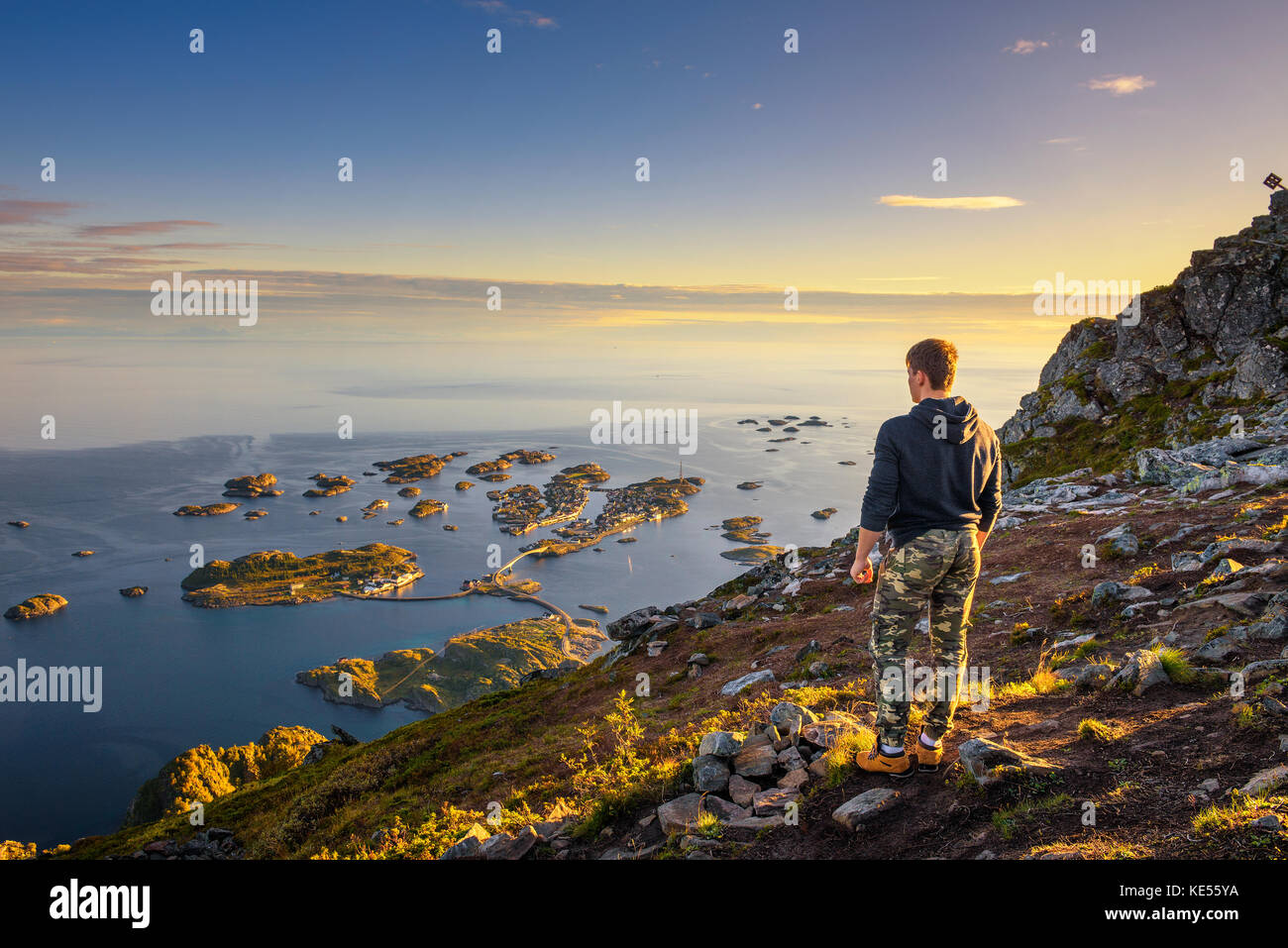 Hiker standing at the top of mount Festvagtinden on Lofoten islands in Norway Stock Photo